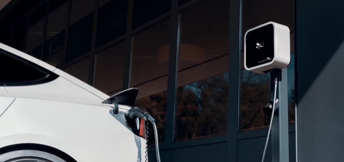 An electric car charging from a wall-mounted destination charger
